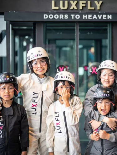 A family in LUXFLY flight suits in front of the wind tunnel